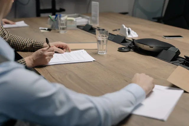 Professional setting of a business meeting with individuals signing documents on a conference table. Zakelijke verkoop aan winkels en bedrijven: offerte, contract en levering